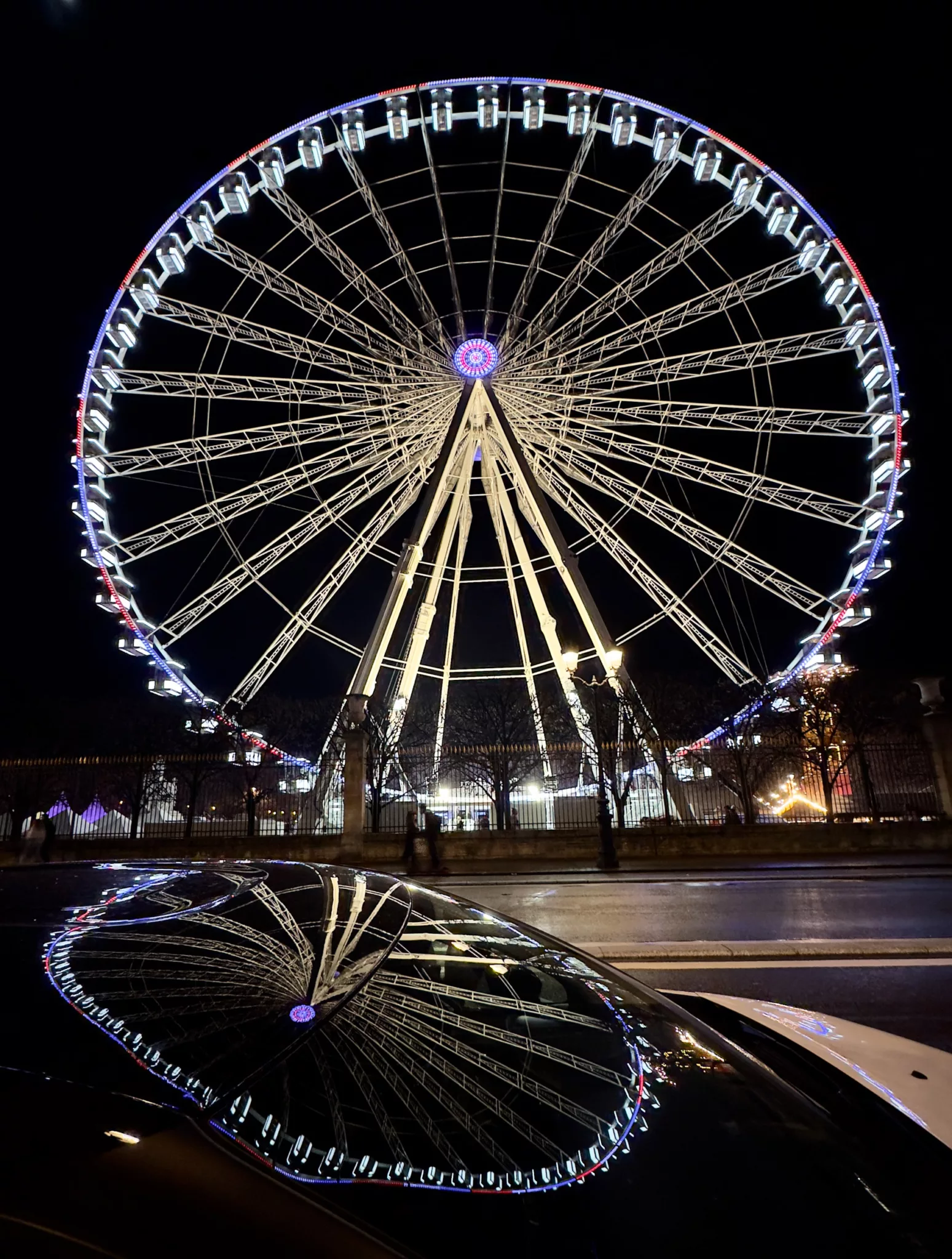 Paris' big wheel (the grande Roue) reflecting in the windshield of a parked car